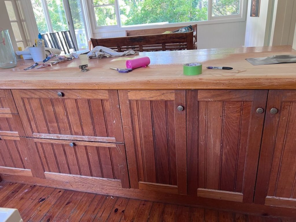 Wooden kitchen island with various tools and items on the countertop in a well-lit room.