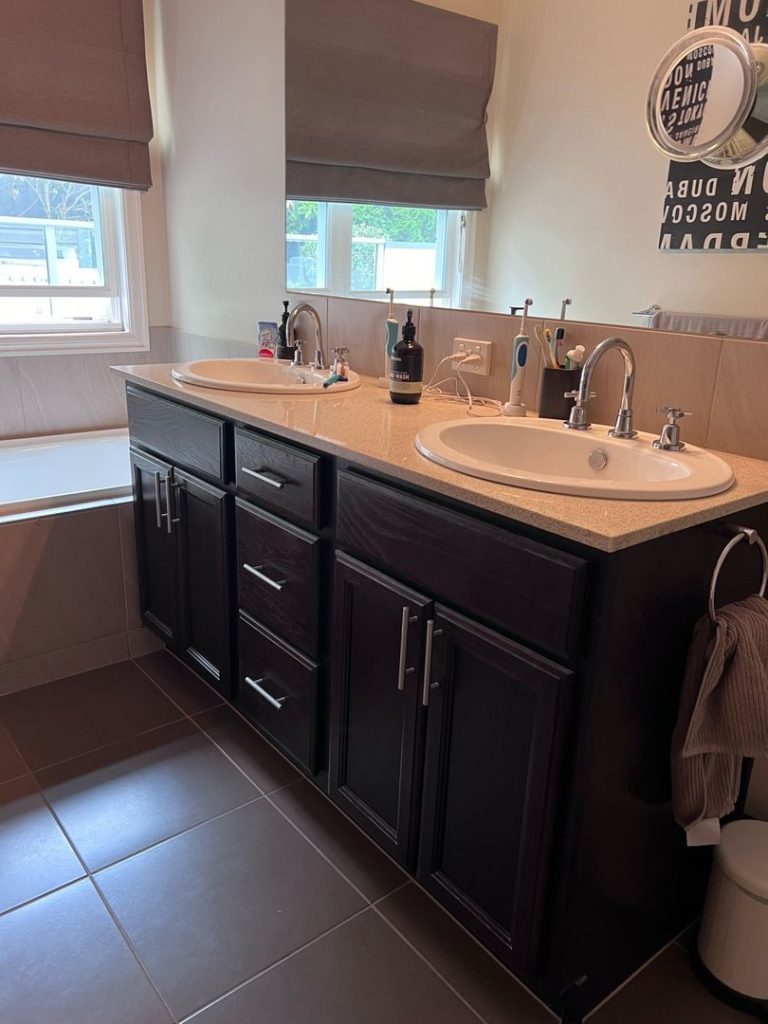 Bathroom with double sink vanity, dark wood cabinets, large mirror, and bathtub.