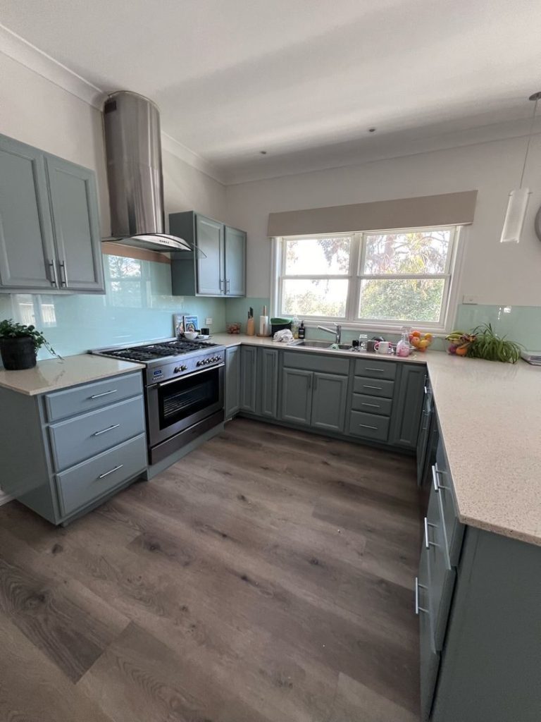 Modern kitchen in Ringwood North with light blue cabinets, stainless steel appliances, and wooden flooring.