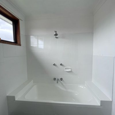 Bathroom with white bathtub, wall-mounted showerhead, and tiled walls