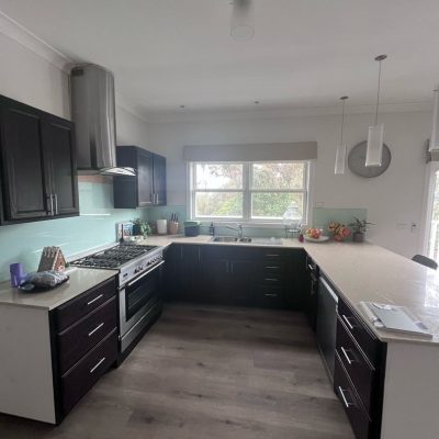 Modern kitchen with dark wood cabinets, stainless steel appliances, and a large island in Ringwood North.