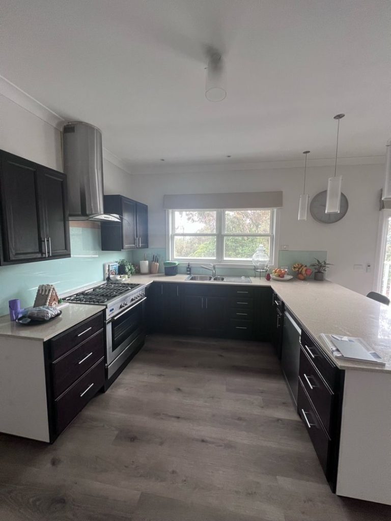 Modern kitchen with dark wood cabinets, stainless steel appliances, and a large island in Ringwood North.