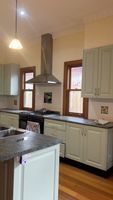 Modern kitchen in Oakleigh with light-colored cabinets, granite countertops, and stainless steel appliances.