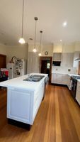 Kitchen with white cabinets, central island, wooden floor, and built-in appliances.