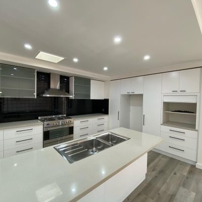 Modern kitchen with white cabinets, stainless steel appliances, black backsplash, and central island.