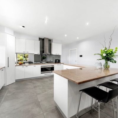 Modern kitchen with white cabinets, light brown countertops, central island, and stainless steel appliances.