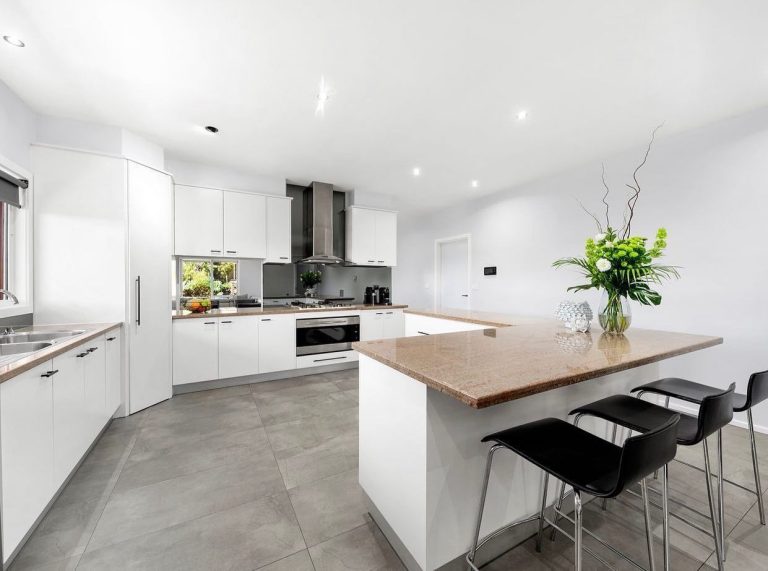 Modern kitchen with white cabinets, light brown countertops, central island, and stainless steel appliances.