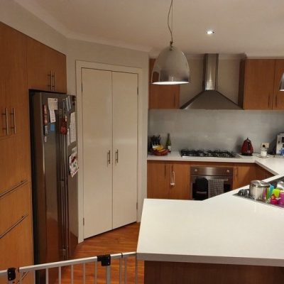 Modern kitchen with wooden cabinets, stainless steel appliances, and a white countertop.