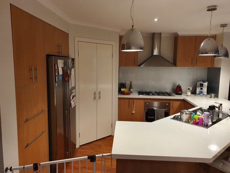 Modern kitchen with wooden cabinets, stainless steel appliances, and a white countertop.