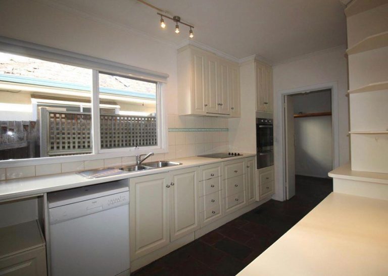 Modern kitchen featuring white cabinets, a benchtop with an integrated sink and dishwasher, a stovetop, and an oven.