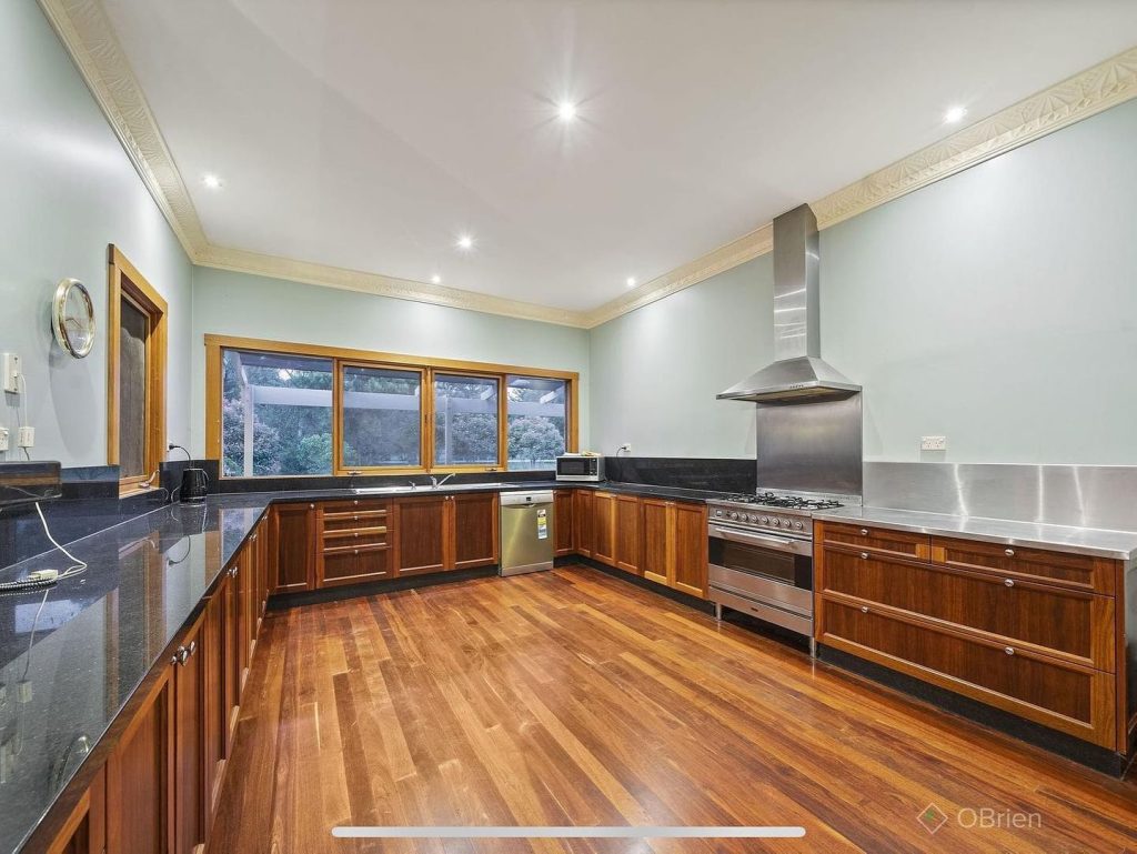 Kitchen with timber cabinets, granite countertops, stainless steel appliances, and large windows.