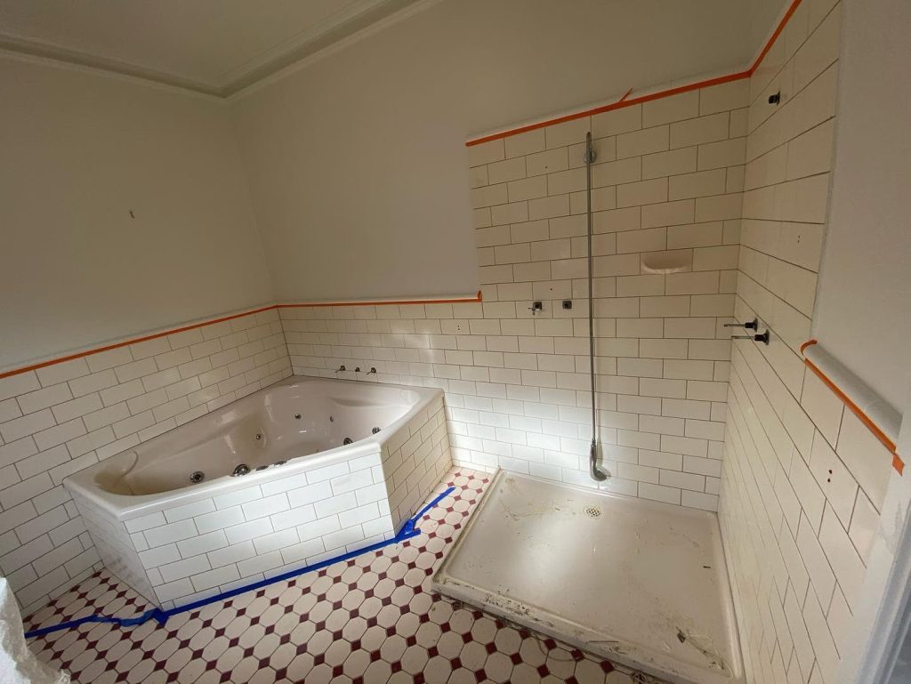 Bathroom under renovation with white subway tiles, jet bathtub, and shower area.