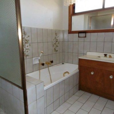 Bathroom with bathtub, wooden vanity, and tiled walls.