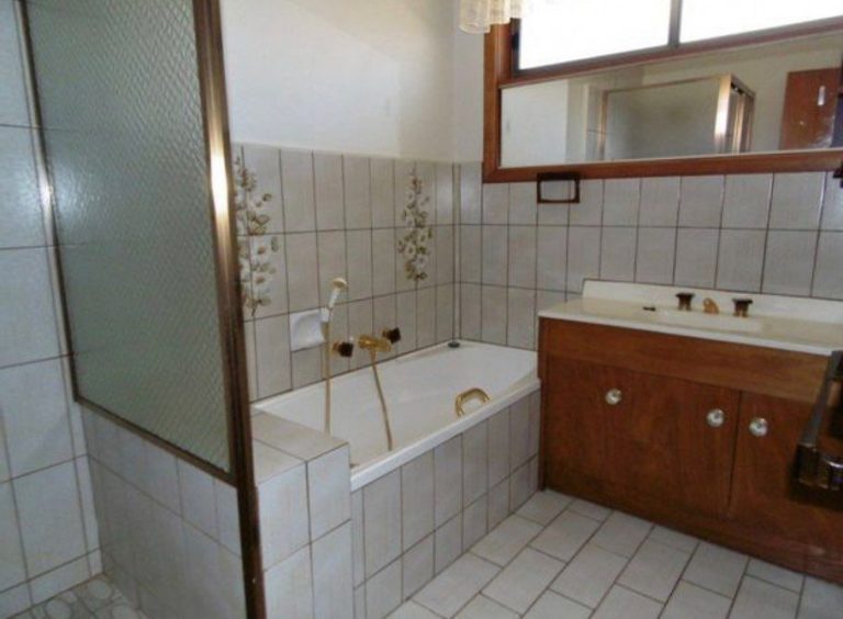 Bathroom with bathtub, wooden vanity, and tiled walls.