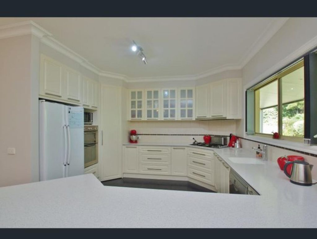 Modern kitchen with resurfaced white cabinetry and red appliances.