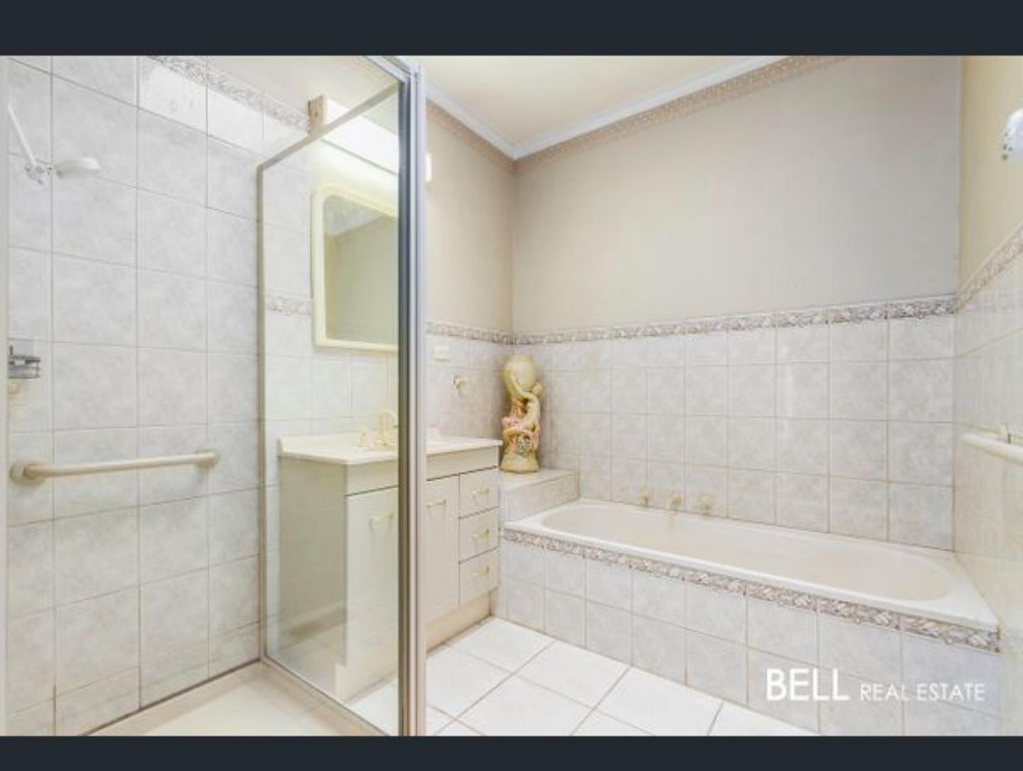 Bathroom with tiled walls, glass shower enclosure, white vanity, and bathtub.