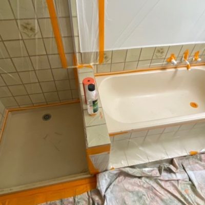 Bathroom being prepared for resurfacing with protective coverings and materials in place.