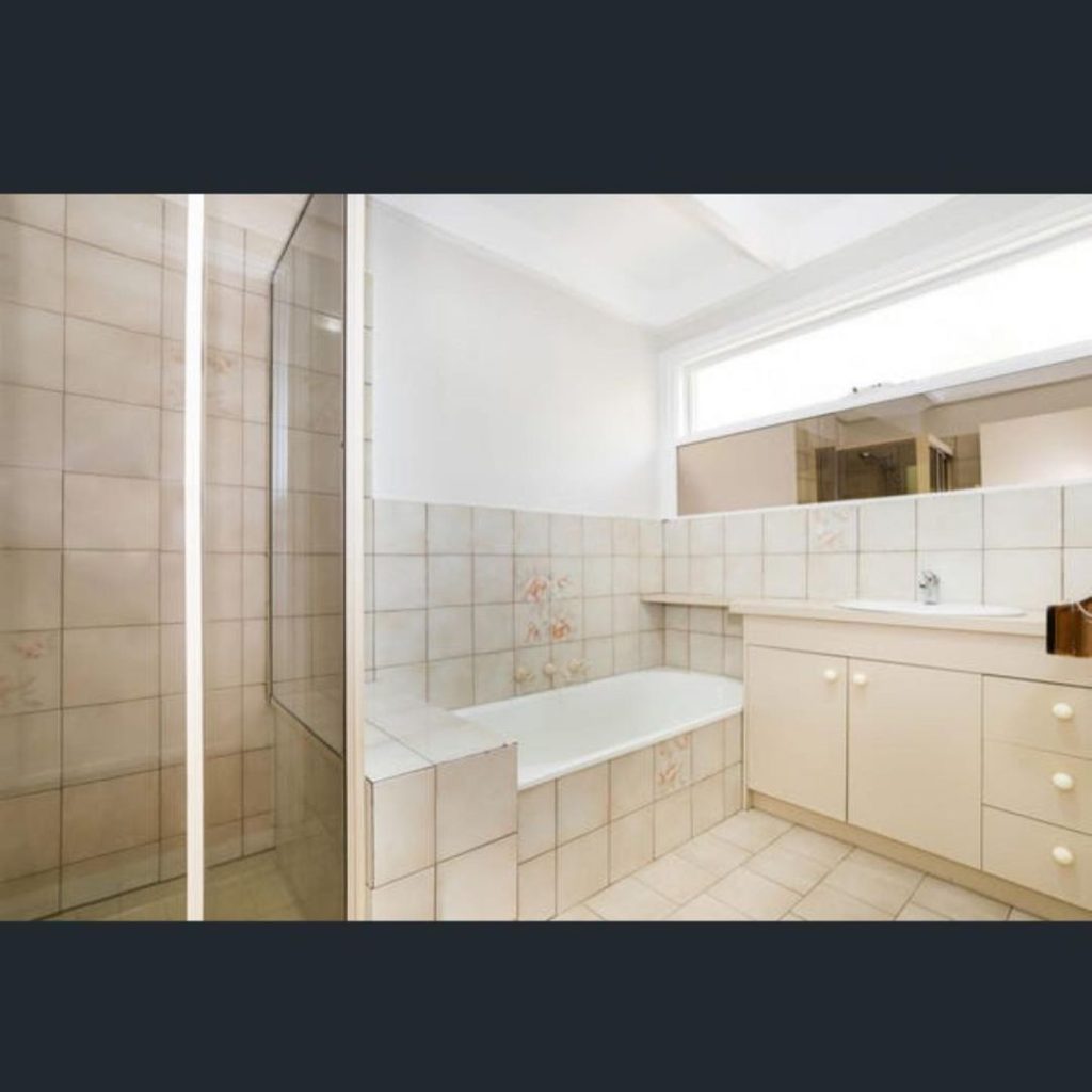 Bathroom with beige tiles, bathtub, shower enclosure, and sink area.