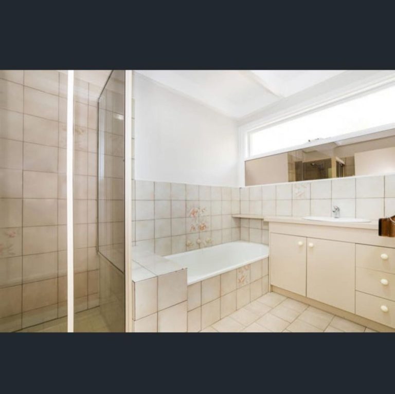 Bathroom with beige tiles, bathtub, shower enclosure, and sink area.