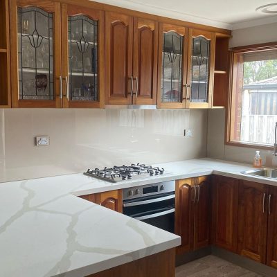 Modern kitchen with wooden cabinets, marble-like countertops, and stainless steel appliances.