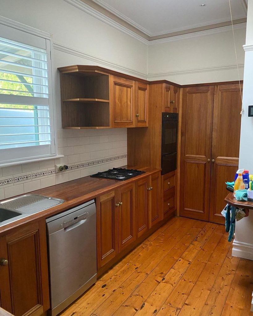 Kitchen with wooden cabinets, gas stove, built-in oven, stainless steel dishwasher, and white tiled backsplash.