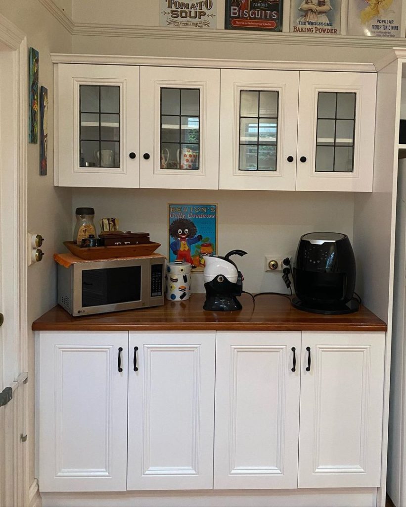 Modern kitchen with white cabinets, wooden countertop, microwave, coffee maker, and air fryer.