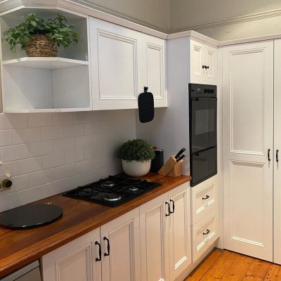 Modern kitchen with white cabinets, wooden countertops, built-in gas stove, and integrated wall-mounted oven.