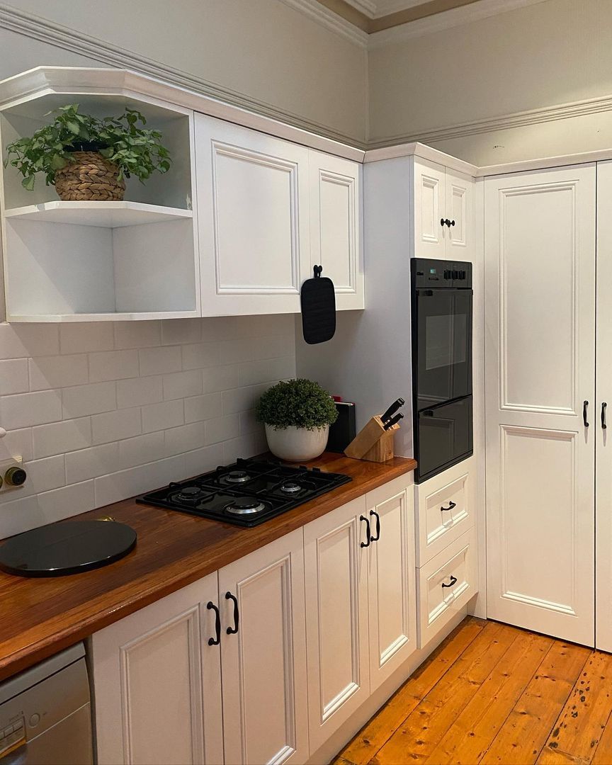 Modern kitchen with white cabinets, wooden countertops, built-in gas stove, and integrated wall-mounted oven.