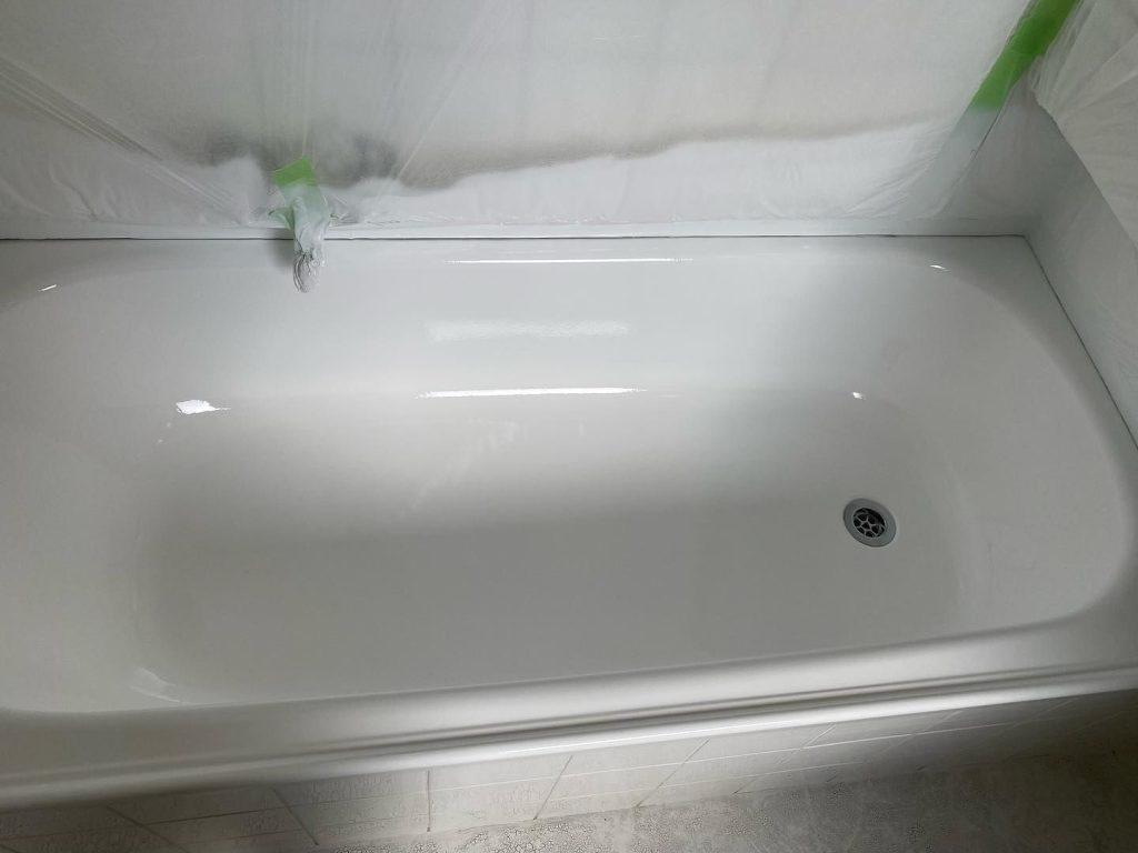 Freshly resurfaced white bathtub with protective plastic sheeting around it.