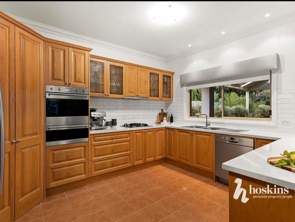 Modern kitchen with wooden cabinets, stainless steel appliances, white subway tile backsplash, and terracotta floor tiles.