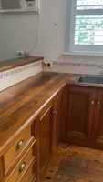 Image of a kitchen with wooden cabinets, countertops, stainless steel sink, and wall-mounted air conditioning unit.