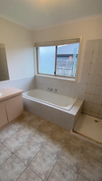 Image of a bathroom under renovation with a bathtub, vanity, and tiled floor.