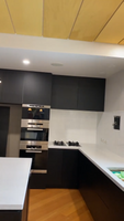 Modern kitchen featuring black cabinets, double ovens, gas stovetops, and white countertops.