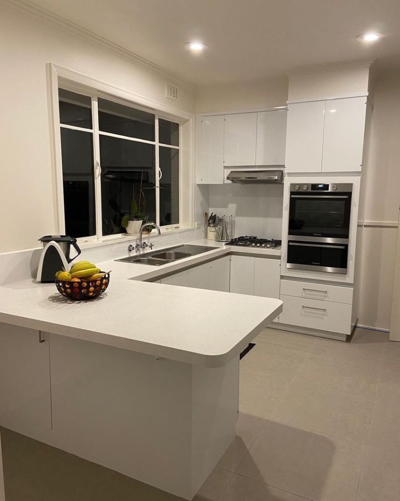 Renovated kitchen with white cabinets, stainless steel appliances, and an island.