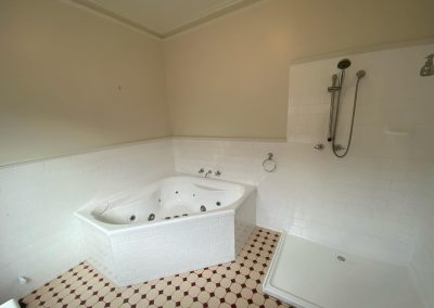 Bathroom renovation showing a corner bathtub with jets, walk-in shower, and tiled walls.