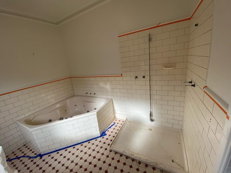 Partially renovated bathroom with new bathtub and tiled walls.