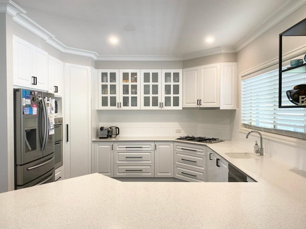 Modern kitchen with stainless steel appliances, white cabinetry, and quartz countertops.