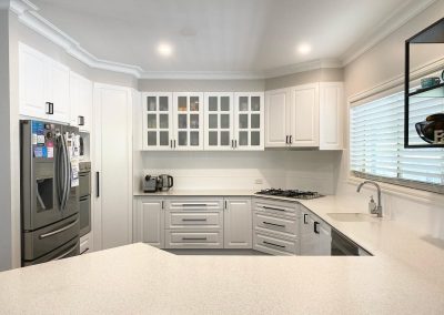 Modern kitchen with stainless steel appliances, white cabinetry, and quartz countertops.