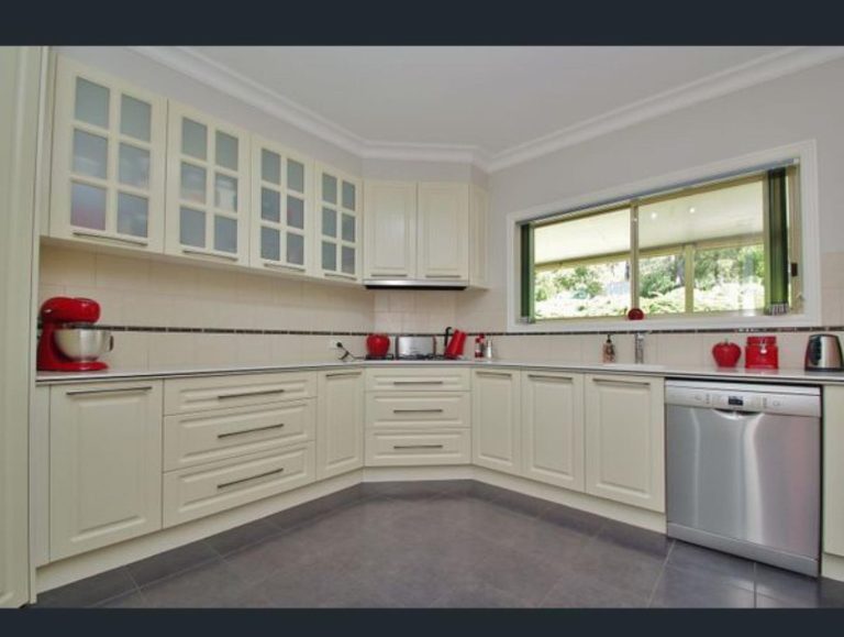 U-shaped kitchen with white cabinets and red appliances including a stand mixer, kettle, and toaster.