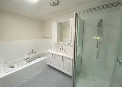 Renovated bathroom with bathtub, glass-enclosed shower, and vanity unit.