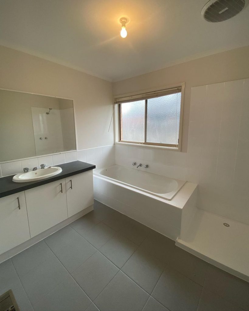 Bathroom with sink, countertop, bathtub under a window, and a shower area.