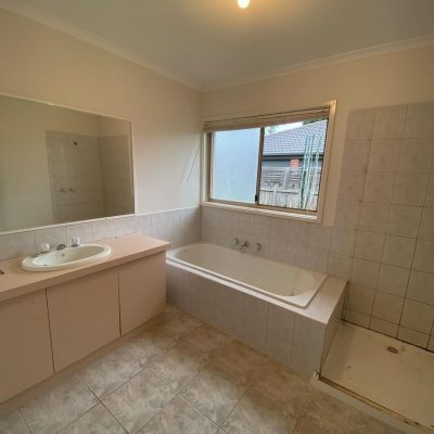 Residential bathroom under renovation with visible sink, bathtub, shower area, and large mirror.