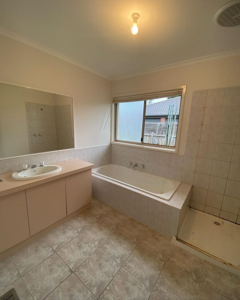 Residential bathroom under renovation with visible sink, bathtub, shower area, and large mirror.