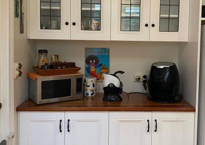 Kitchen section featuring white cabinetry, a microwave, coffee maker, air fryer, and vintage decor signs.