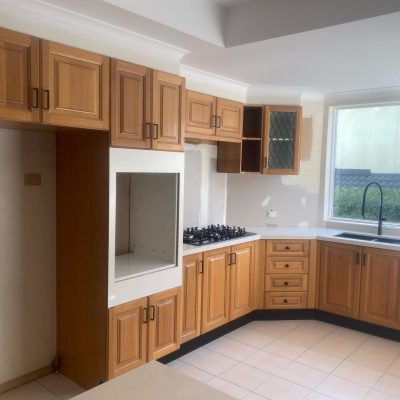 Kitchen under renovation with wooden cabinets, gas stovetop, and large window.