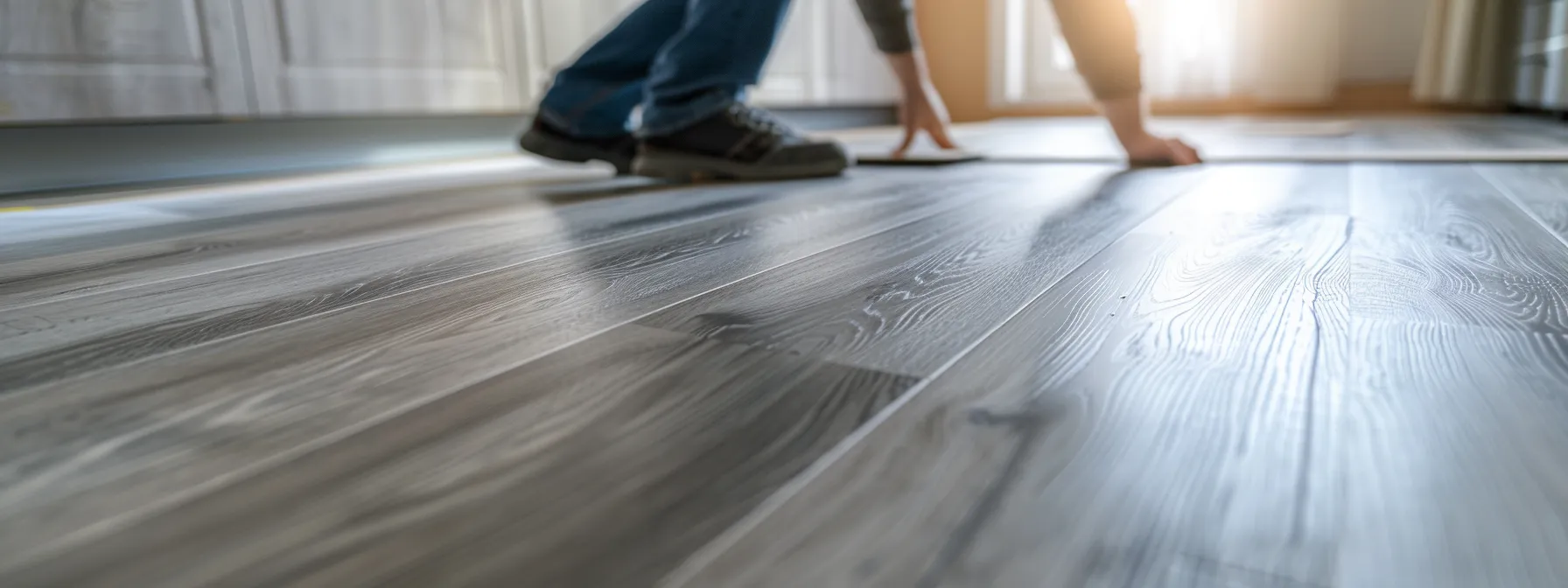 a person laying down vinyl flooring in a kitchen with a modern and affordable design.