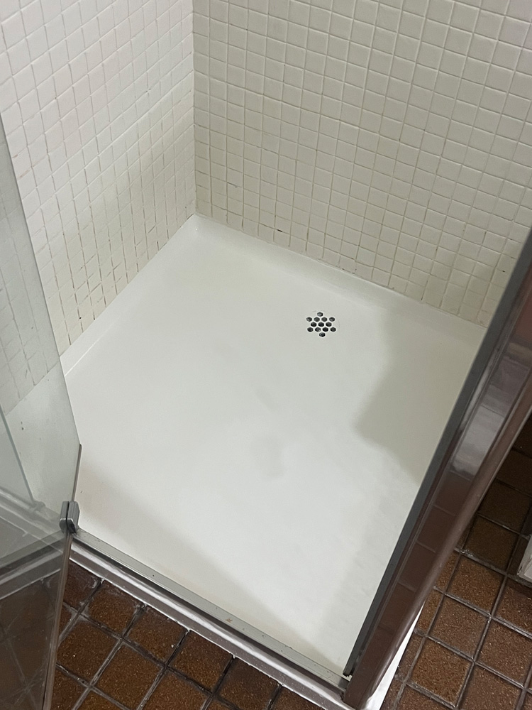 White bathtub with glossy finish and protective plastic sheeting in a bathroom under renovation.